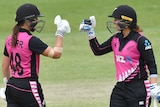 Two New Zealand female cricketers prepare to bump fists as they celebrate beating Australia in Brisbane.