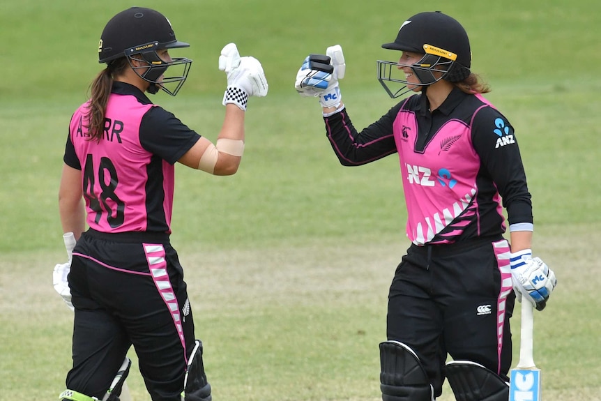 Two New Zealand female cricketers prepare to bump fists as they celebrate beating Australia in Brisbane.