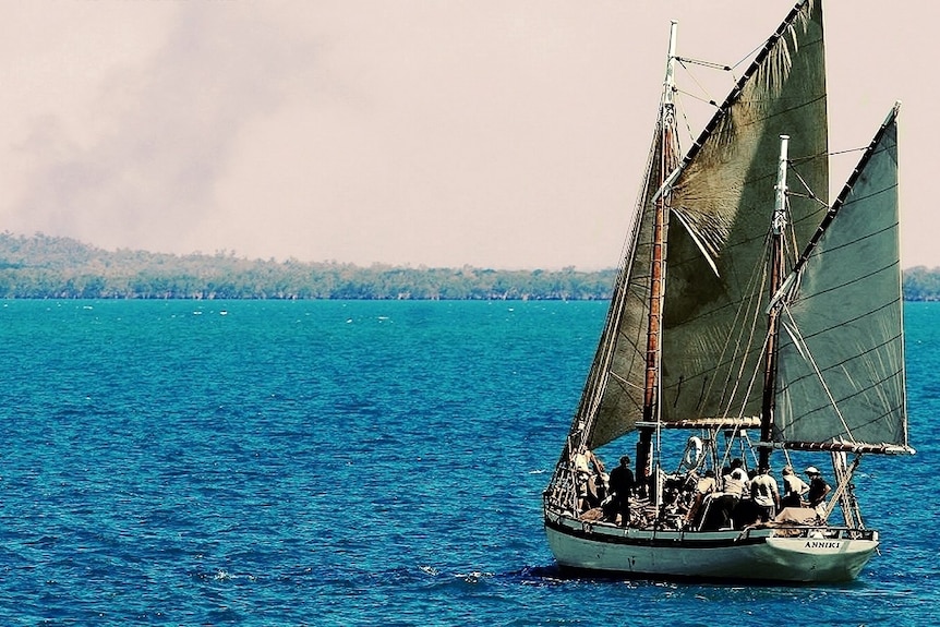 Old wooden sailing ship sailing away from camera toward the mangroves on a nice day.