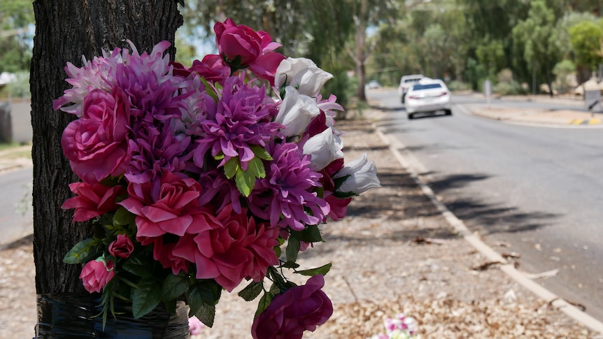 Flowers tied to a tree, mark the memorial site for the victim of fatal hit and run in Alice Springs in May 2022