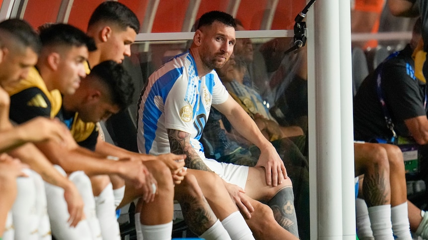 Argentina's Lionel Messi sits on the bench, crying with ice on his ankle