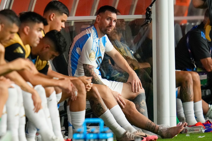 Argentina's Lionel Messi sits on the bench, crying with ice on his ankle