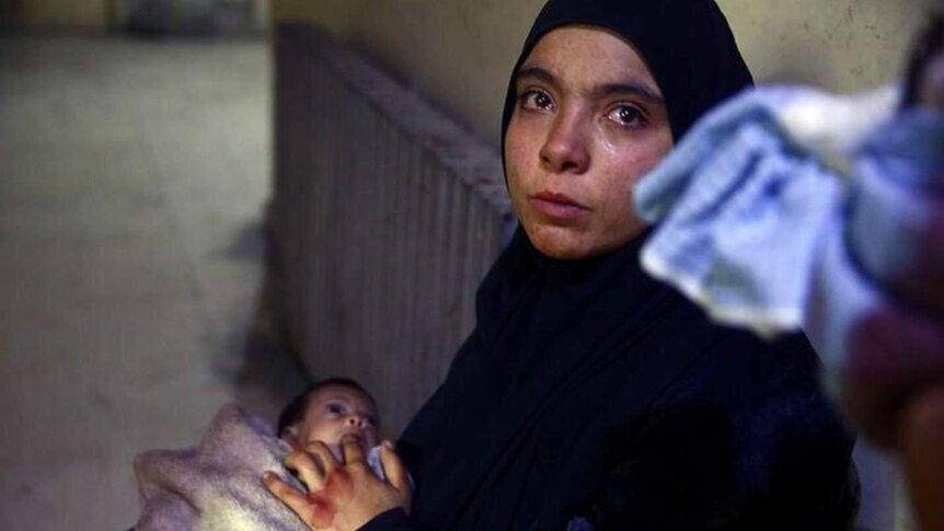 A woman cries while holding a baby in Ghouta