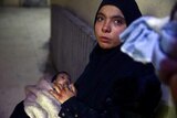A woman cries while holding a baby in Ghouta