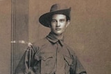 Private Cecil Burns in his Army uniform standing near a wall