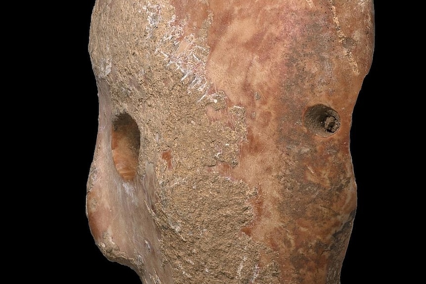 Side-on view of a stone mask with holes in it.