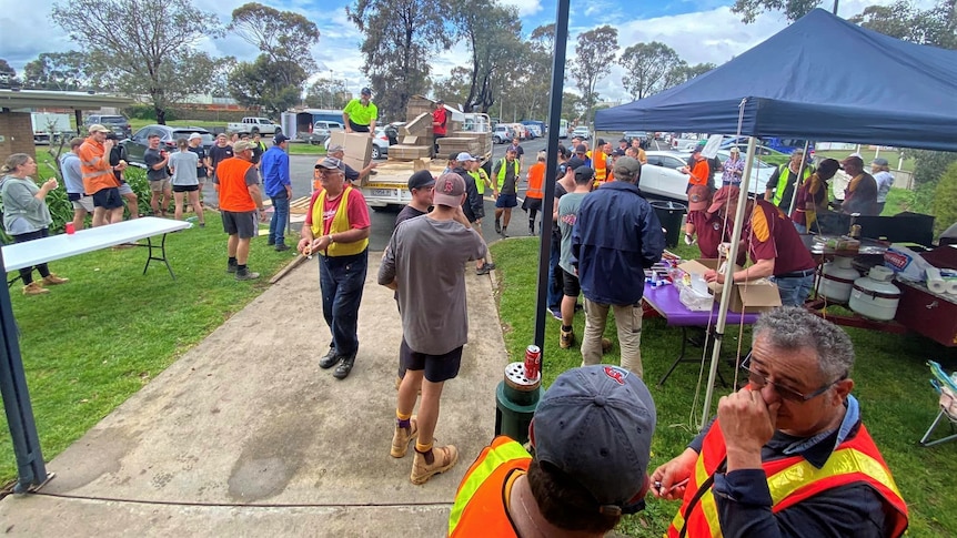 A Lions Club operates a barbecue and dozens of volunteers in high-vis gather on the lawn outside. 