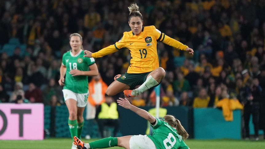 Matildas player Katrina Gorry jumps in air over an England player while playing a soccer match