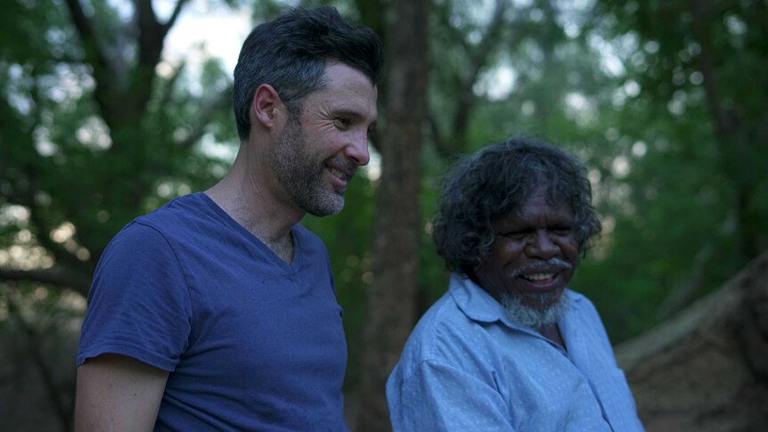 A Caucasian man and an Indigenous man stand side-by-side, smiling.