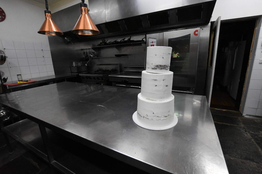 An undecorated wedding cake sitting on a bench in the kitchen of the Euroa Butter Factory.