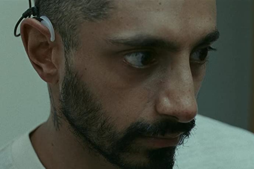 Close-up of Riz Ahmed looking alert and concerned