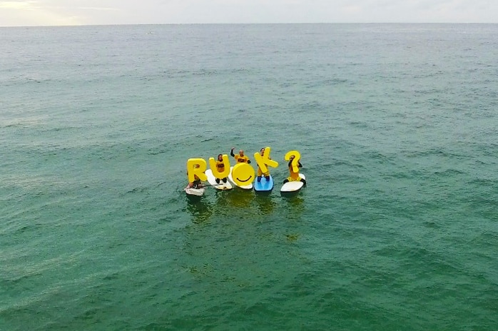 RUOK letters being held by people on surfboards