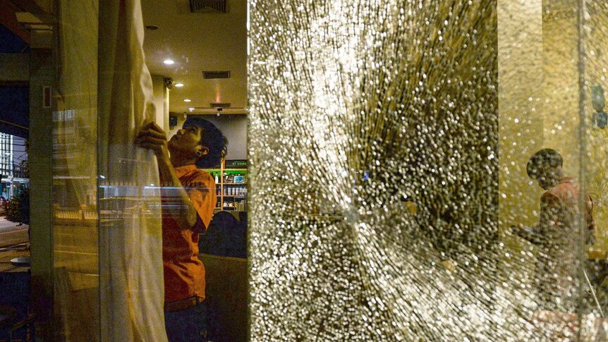 A smashed glass window and a labourer where a bomb attack took place earlier.