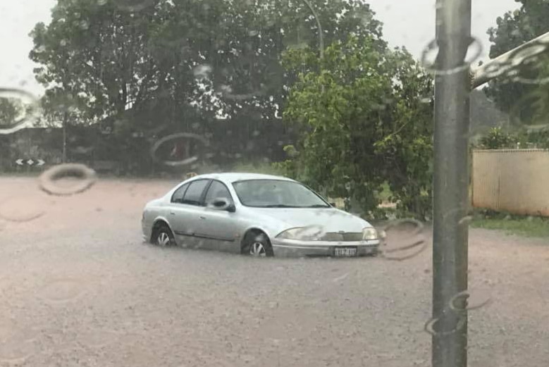 A car sits stranded in muddy floodwaters on the side of a road in Broome.