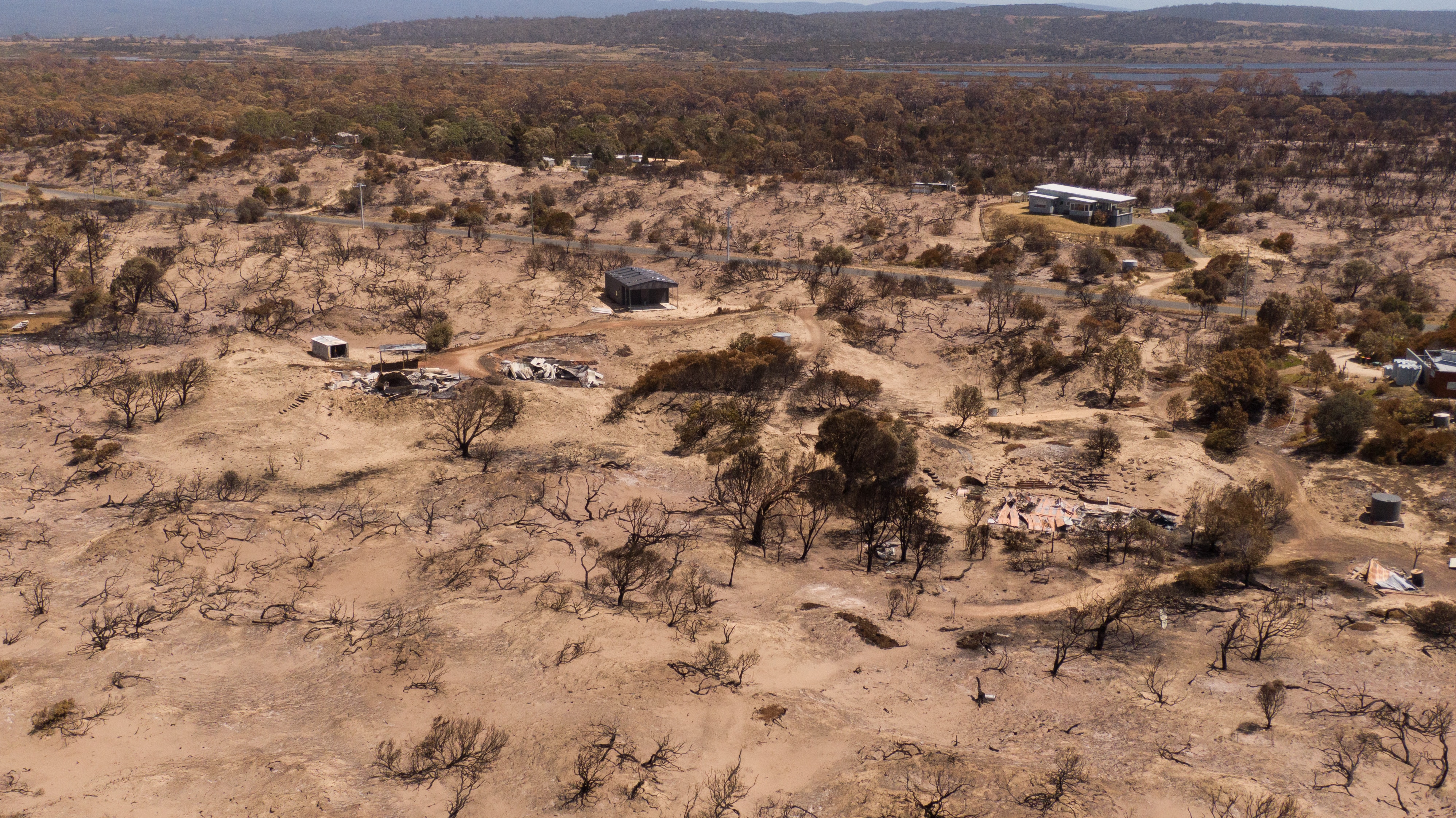 Fotos de drone de um enclave à beira-mar com vegetação queimada.