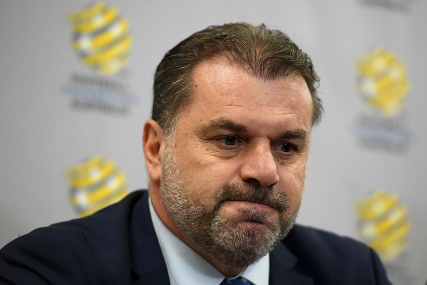 Ange Postecoglou sits in front of microphones at a press conference.