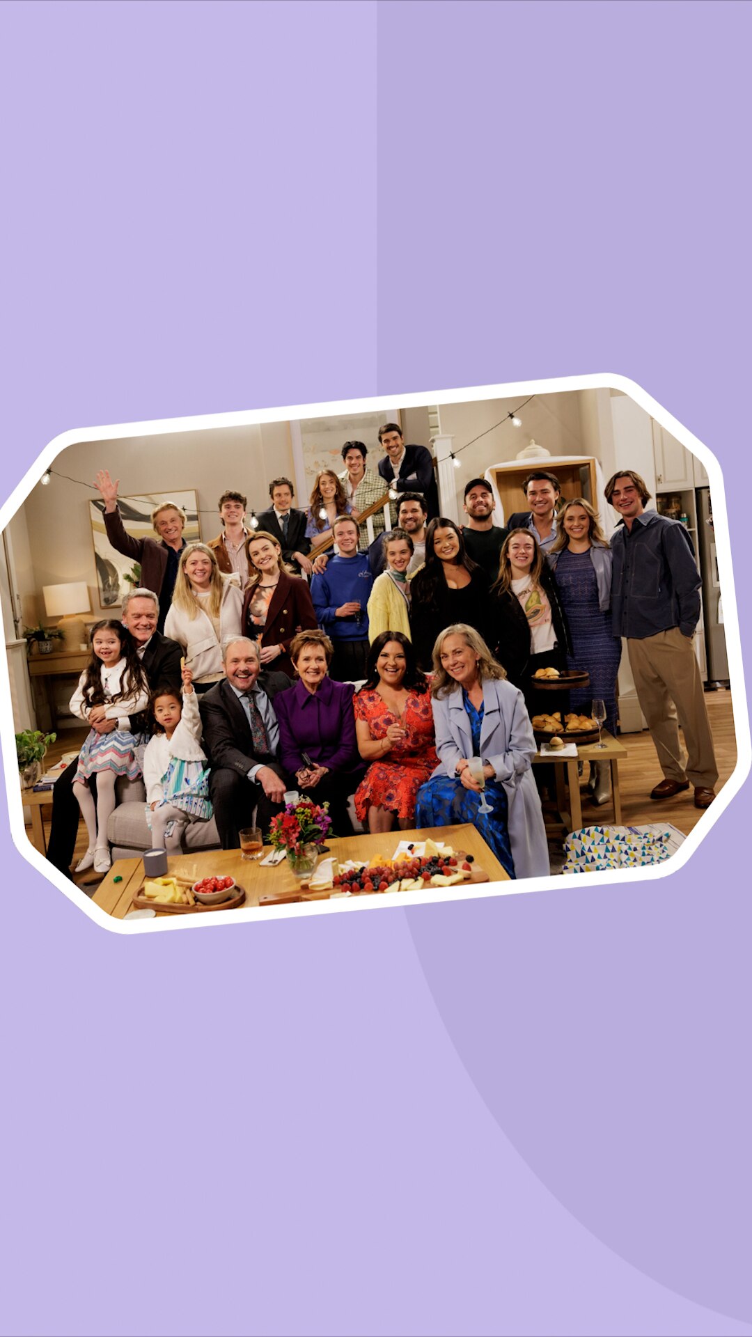 A group photo of about a dozen of people in a living room which appears to be a film set.