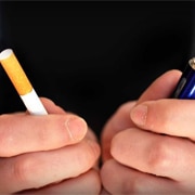 A person holds a tobacco cigarette in one hand and an electronic cigarette in the other.