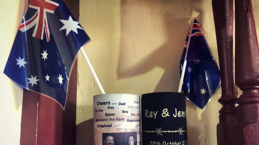 Two stubby holders sit with Australian flags on a pub shelf