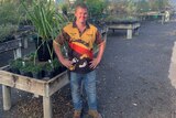 Damien Beveridge stands beside a tray of plants at a Dubbo nursery, he enjoys growing plants from seed.