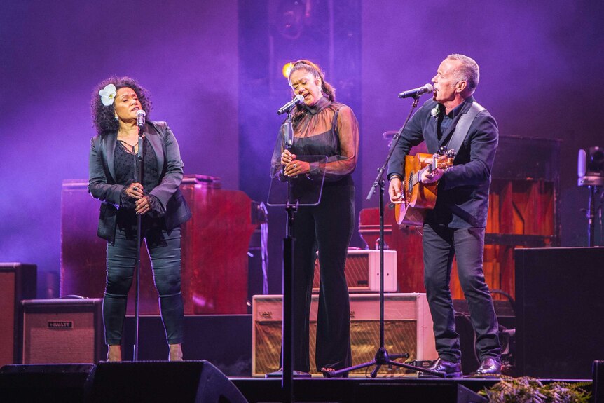 Vika and Linda Bull and Mark Seymour sing on stage at the Michael Gudinski state memorial