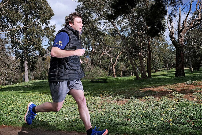 Tim Smith runs through a park on a sunny day