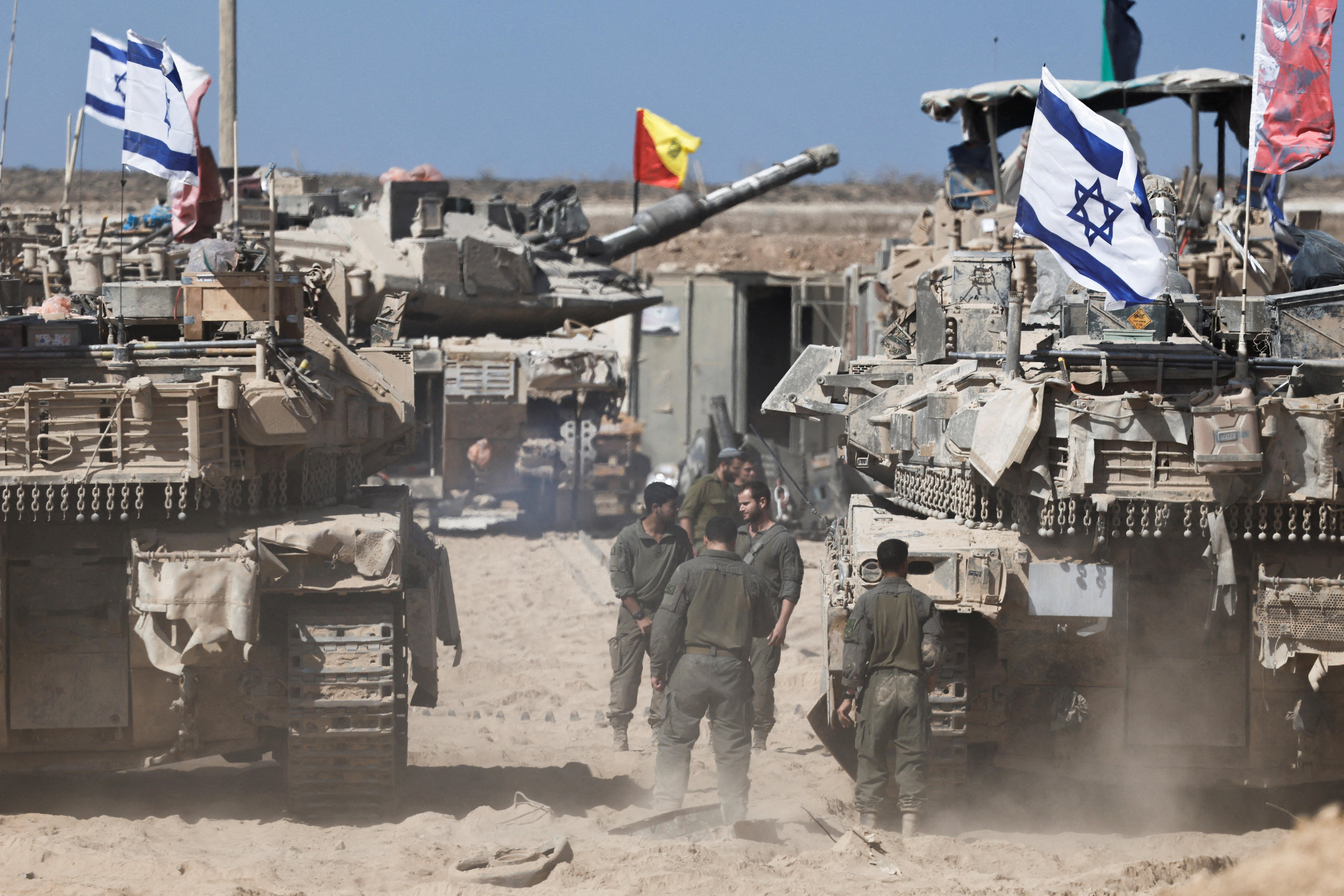 Israeli soldiers stand next to tanks near the Israel-Gaza border