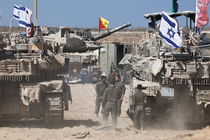 Israeli soldiers stand next to tanks near the Israel-Gaza border
