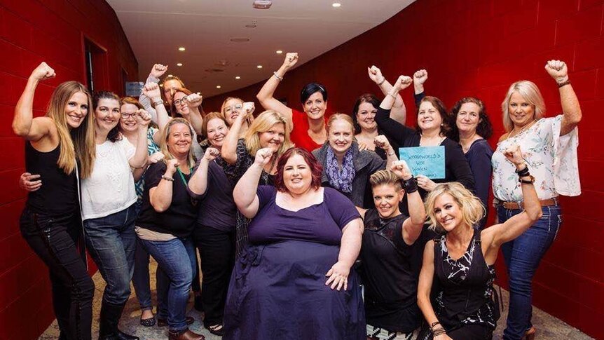 Woman in wheelchair surrounded by a group of women fist pumping