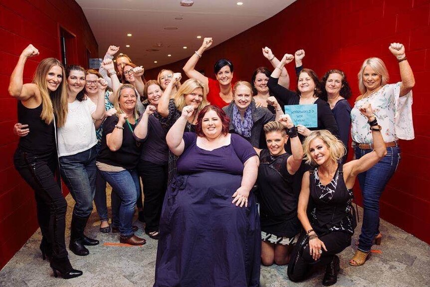 Woman in wheelchair surrounded by a group of women fist pumping