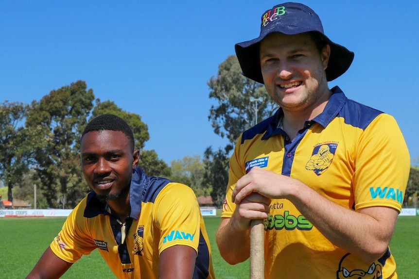 two men in yellow outfits one wearing blue hat crouch with cricket bat