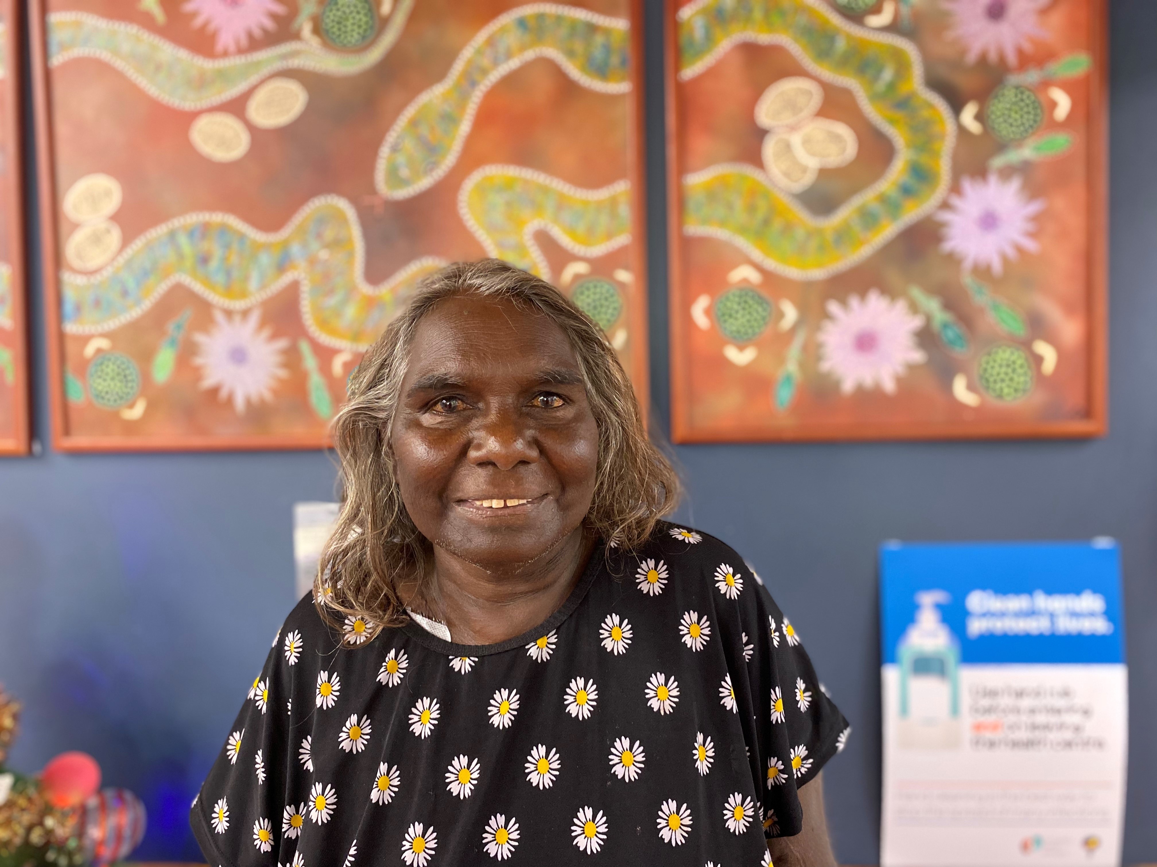 Aboriginal woman standing in front of a painting