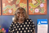 An Aboriginal woman standing in front of a painting.