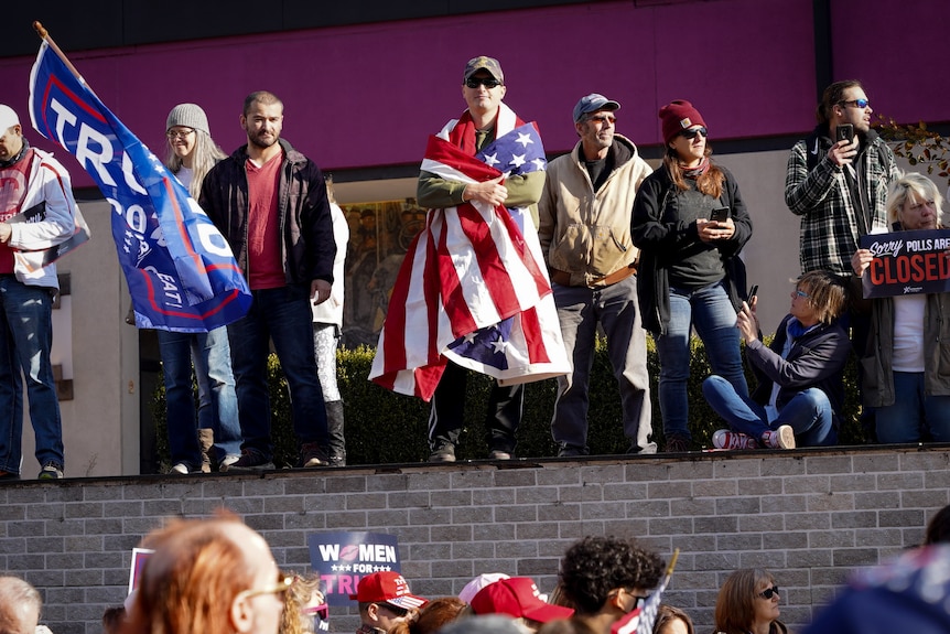 A crowd of Trump supporters, with a man draped in the stars and stripes in the centre