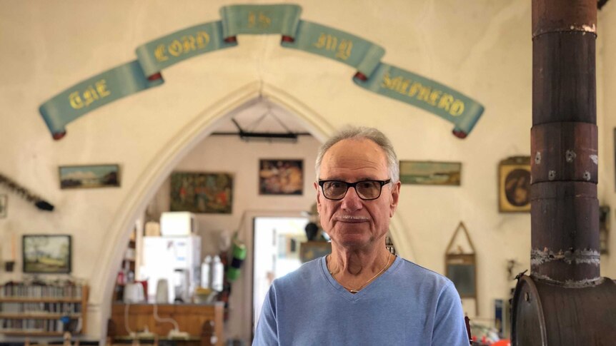 Norbert Scholz standing inside his home, which was once a Lutheran Church, with lots of memorabilia.