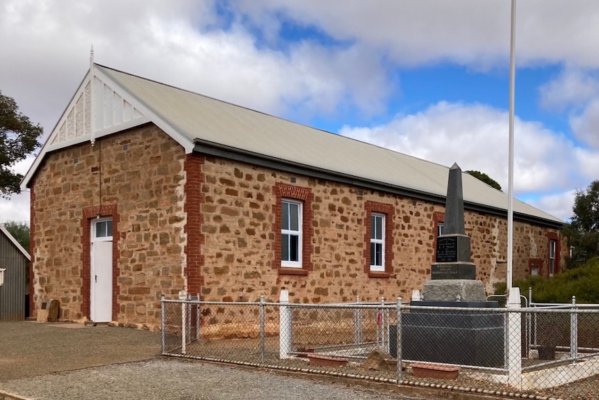 The Yarcowie Hall is made from stone bricks and stands next to a war monument. 