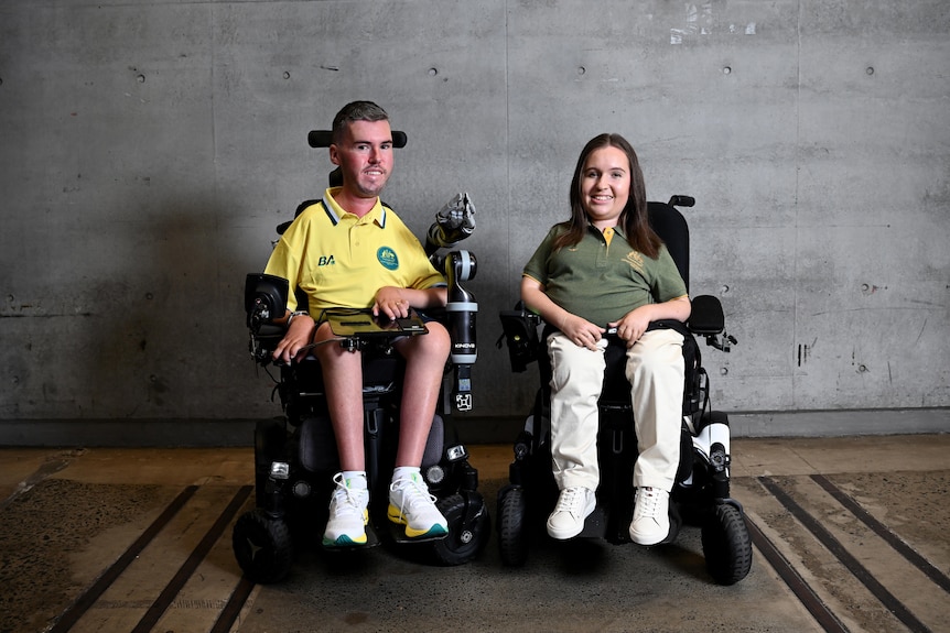 Paralympic boccia athletes Dan Michel and Jamieson Leeson sit in their wheelchair and pose for a photo in Australian uniform