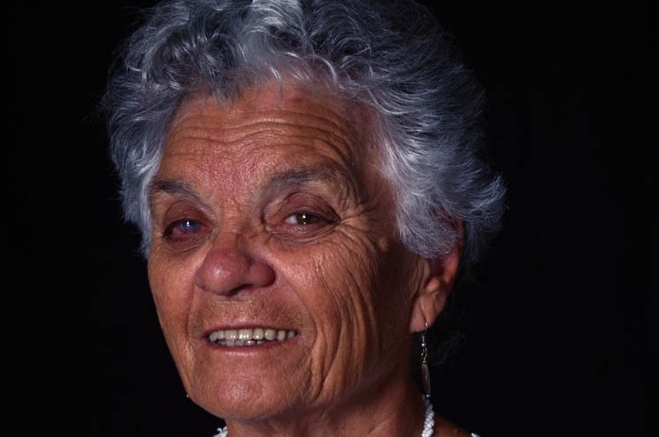 A woman smiles against a black backdrop.