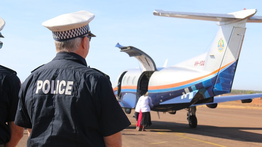 A policeman watches as the body is unloaded from a small plane