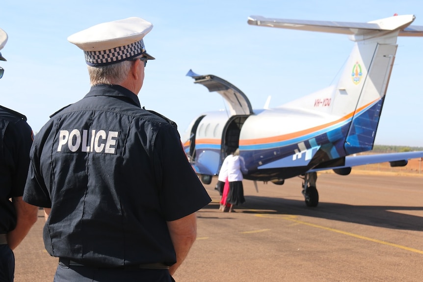 A policeman watches as the body is unloaded from a small plane