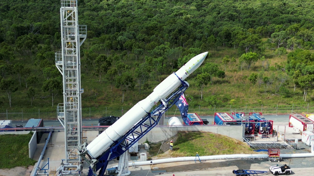 A rocket on scaffolding is lifted up on a launch pad. 