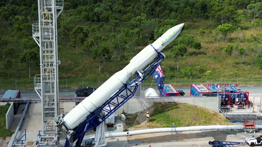 A rocket on scaffolding is lifted up on a launch pad. 