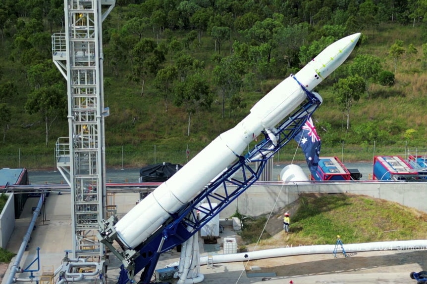 Un cohete sobre un andamio se eleva sobre una plataforma de lanzamiento. 