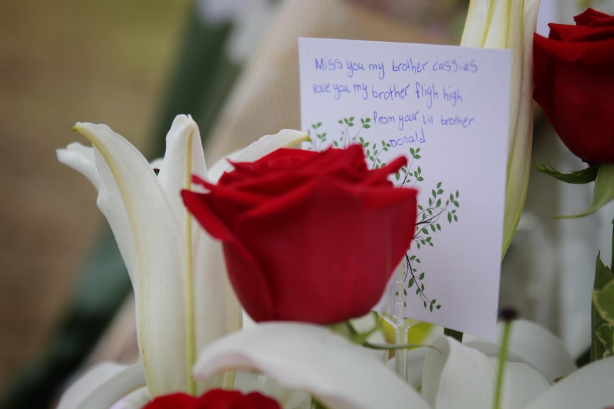 A close up of a red rose and a card written to Cassius Turvey at the site of a memorial to the 15-year-old