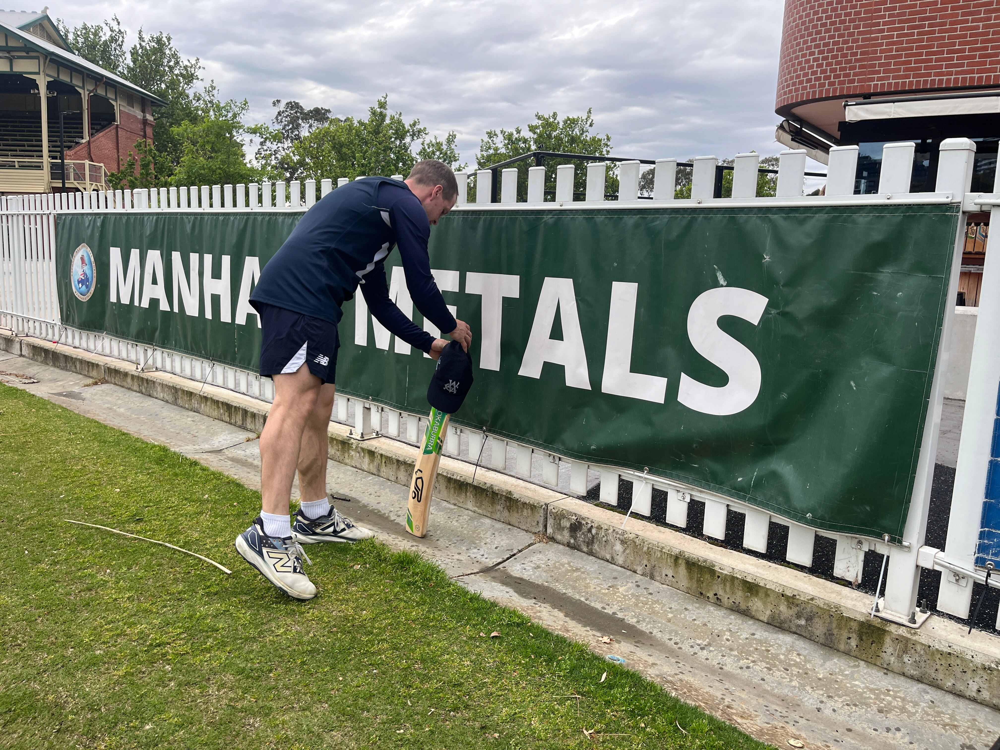 A player laying a cricket bat against a fence