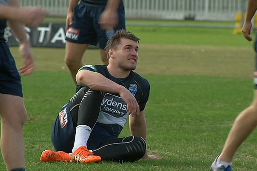 Angus Crichton sits on the ground while his NSW State of Origin teammates train
