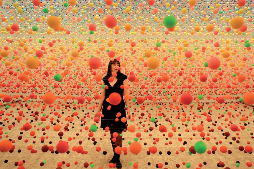 An artwork of a woman stands amongst floating balls in