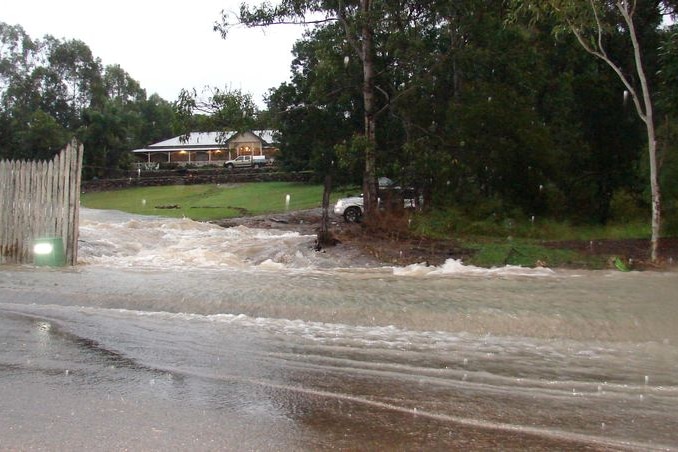 Water from a ruptured water pipe pours down Mt Crosby Road