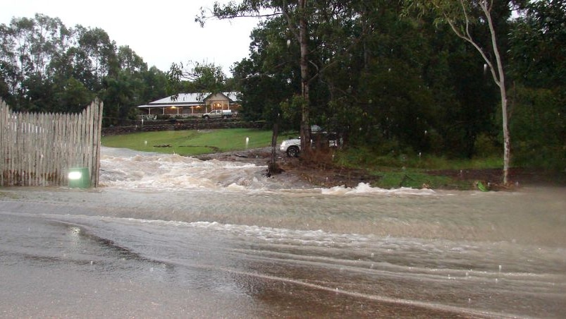 Water from a ruptured water pipe pours down Mt Crosby Road