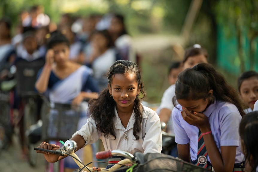 A young girl looks at the camera as her friend laughs.